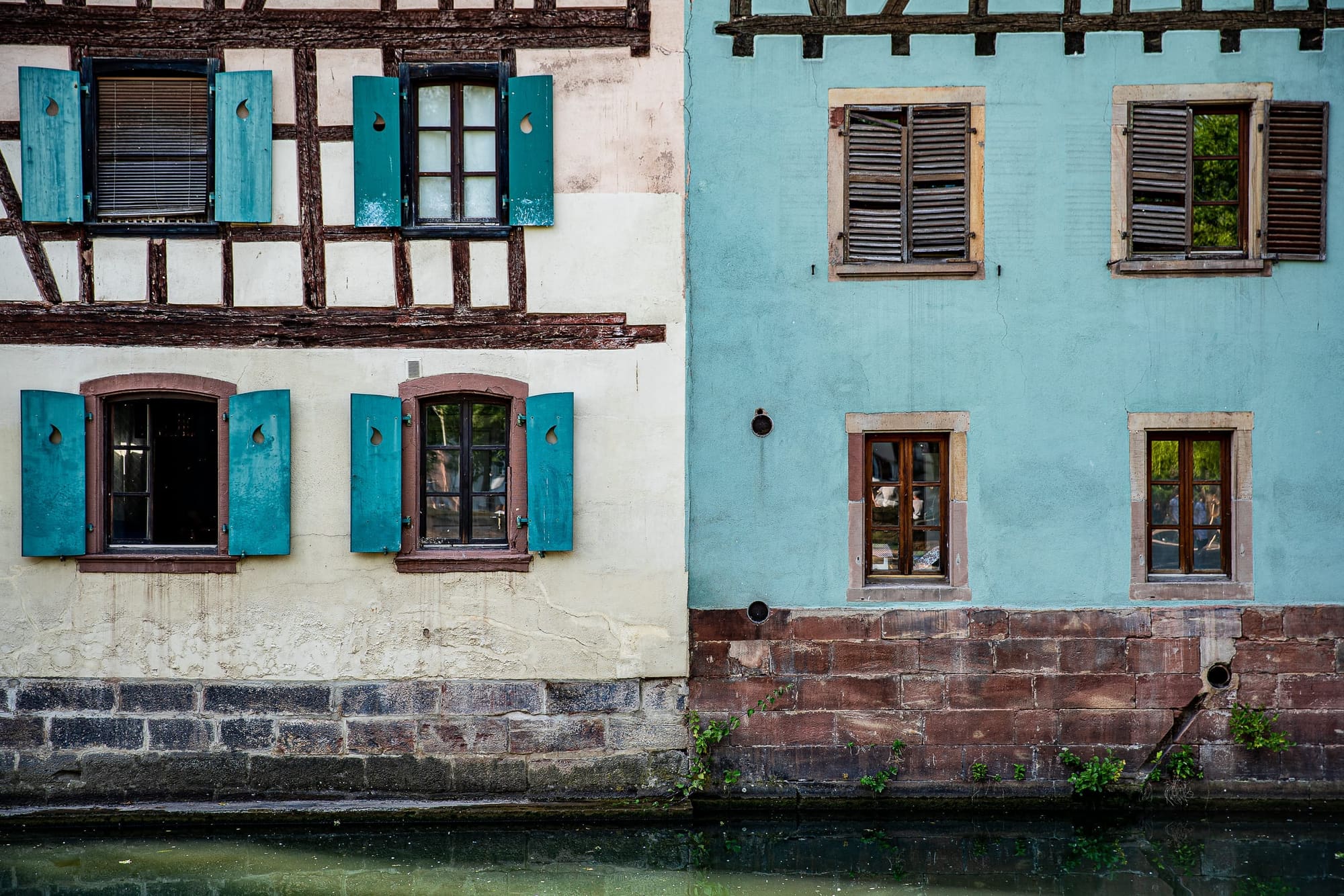 Maison ancienne aux volets bleus au bord d’un canal de la Petite France