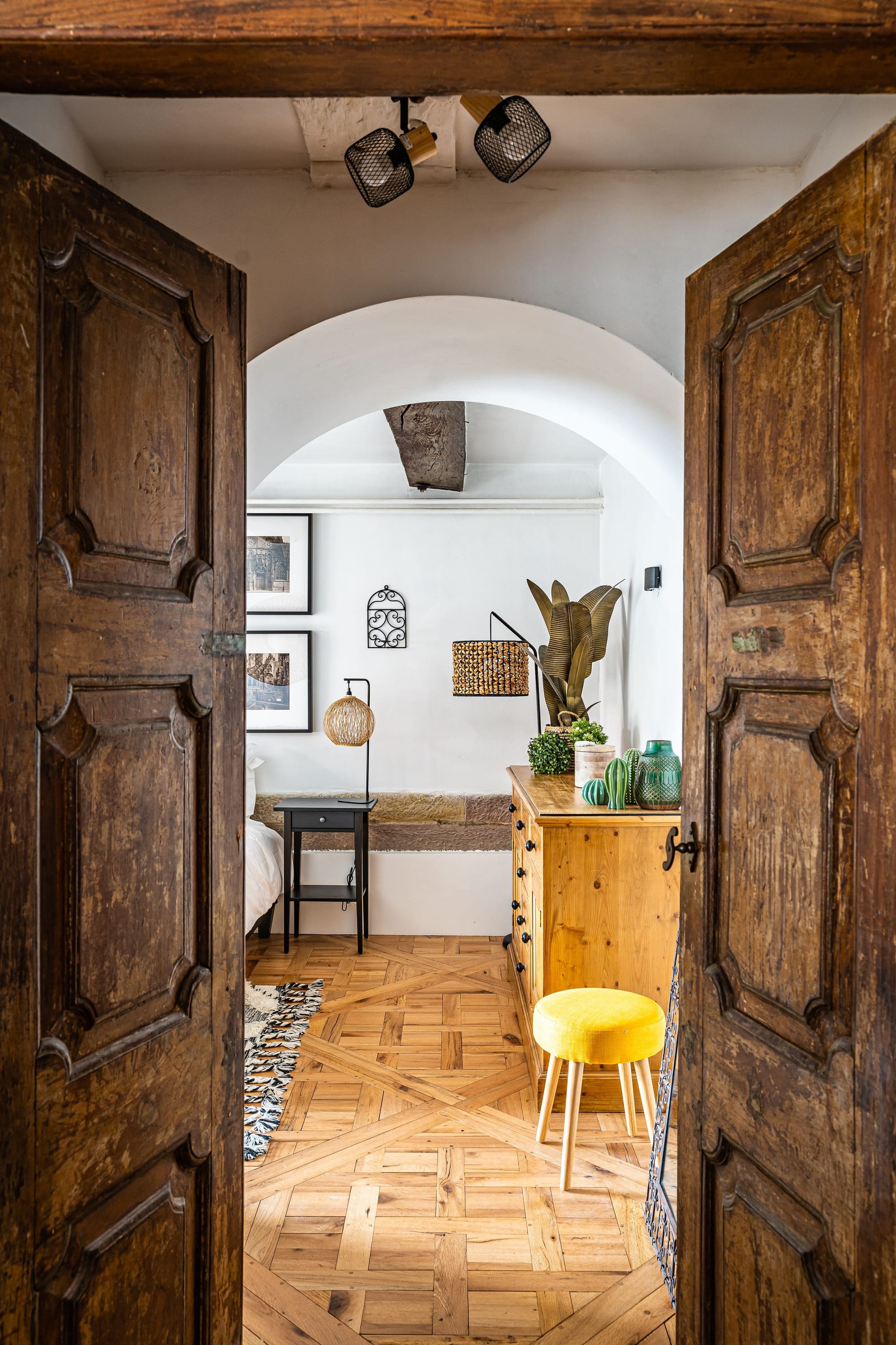 Les portes anciennes à deux battants du Moulin, ouvertes sur la première chambre : parquet en marqueterie, commode de pin et tabouret jaune