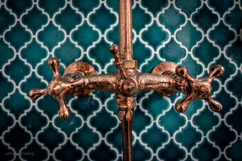 Le robinet de cuivre sur la faïence émeraude de la salle de bain
