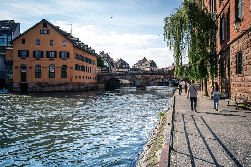 Le Moulin aux Épices vu du quai d'en face : la bâtisse ocre posée sur l'Ill, à côté du pont de pierre