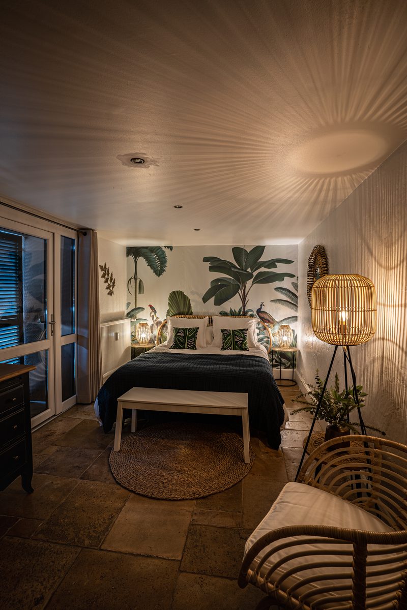 La seconde chambre le soir : fresque végétale, lit bleu nuit et lampes en rotin
