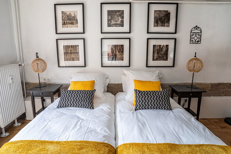 Les deux lits de la chambre sous une série de gravures anciennes