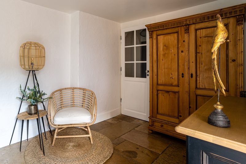 Un coin de repos : fauteuil en rotin, armoire ancienne en bois et sol de grès