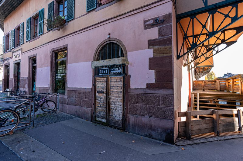 Une façade rose et grès des Vosges, sa porte en plein cintre et ses vélos