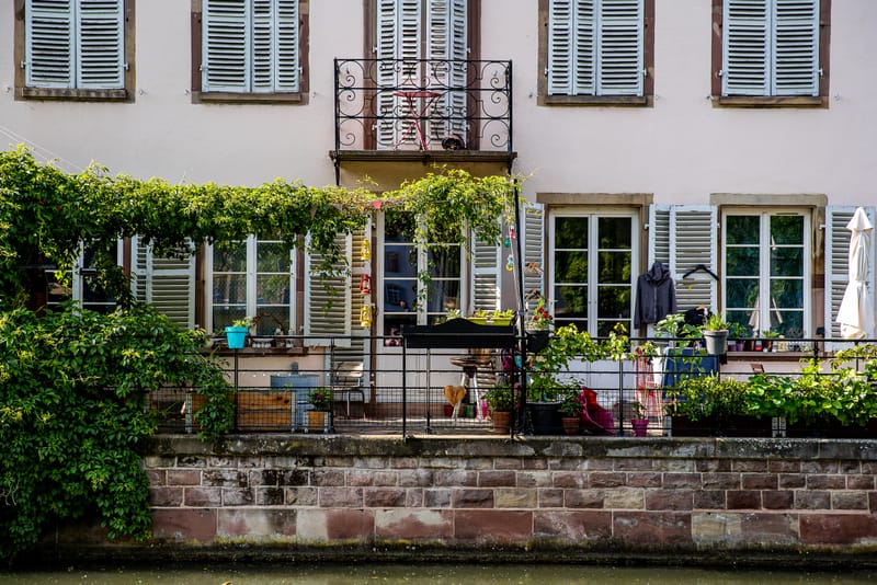 Une maison rose de la Petite France, son balcon de fer forgé et ses plantes au bord du canal