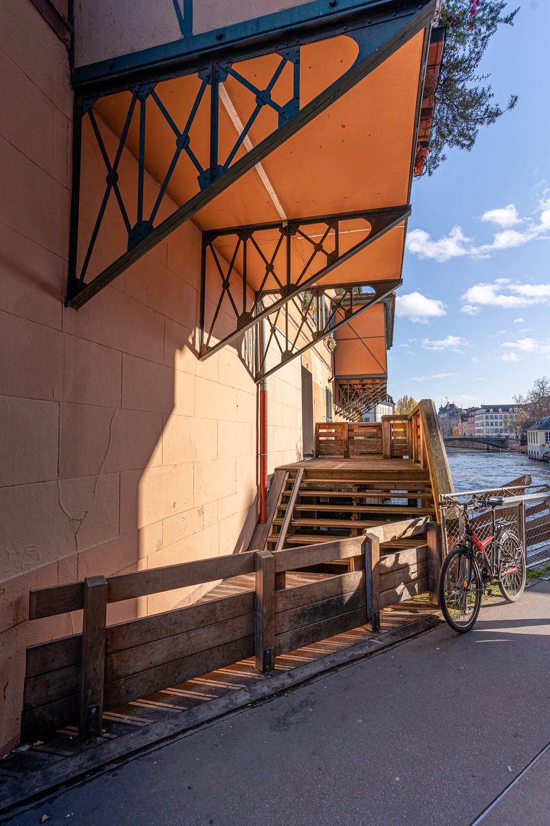 Une marquise de fer forgé et un escalier de bois, au bord du quai