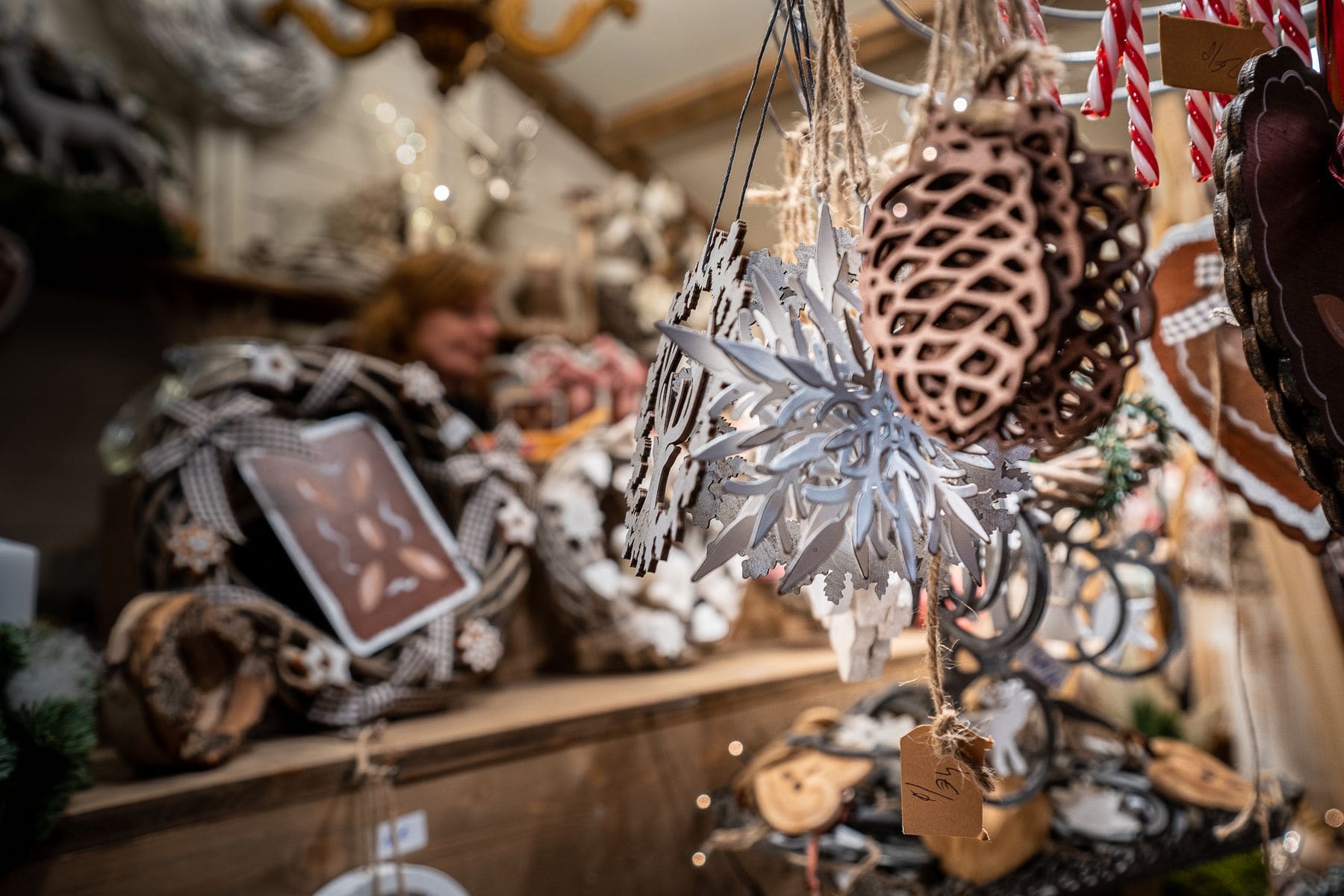 Décorations de Noël suspendues à un chalet du marché de Noël de Strasbourg : étoiles, pommes de pin et biscuits en bois