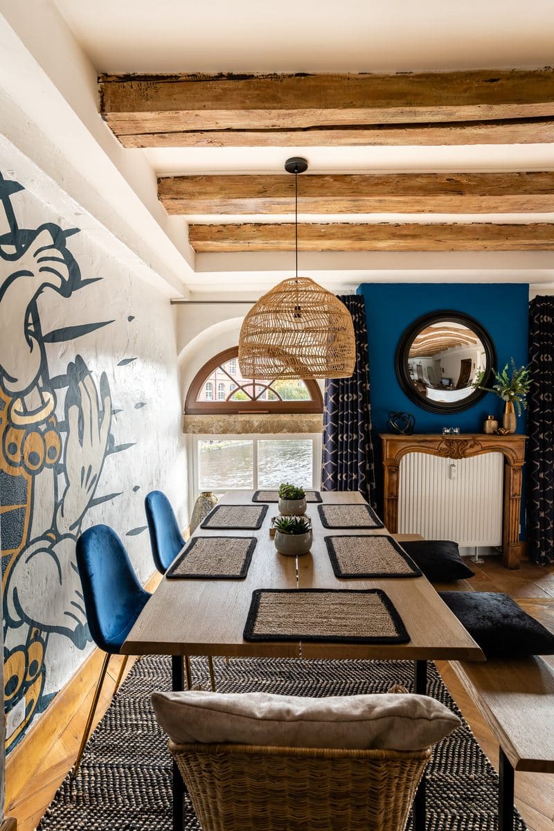 La table à manger en enfilade sous les poutres, vers les fenêtres en plein cintre