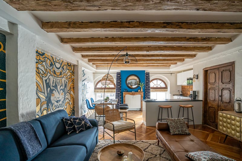 Le salon vu depuis l'entrée : la cheminée, le miroir rond et les deux fenêtres en plein cintre
