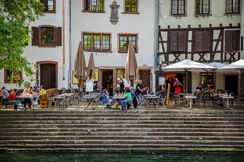 Une terrasse de café installée sur les marches de pierre d'un quai de la Petite France