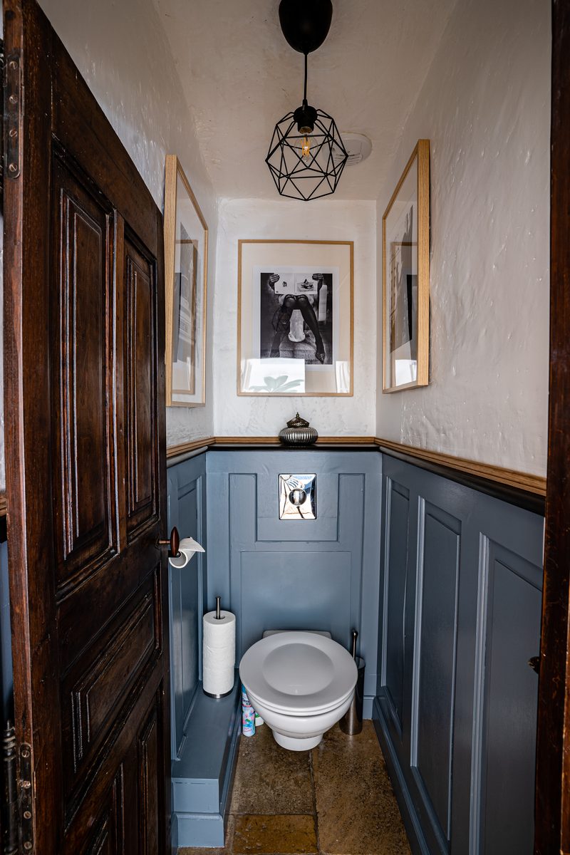 Les toilettes séparées : lambris bleu, porte ancienne et suspension en laiton